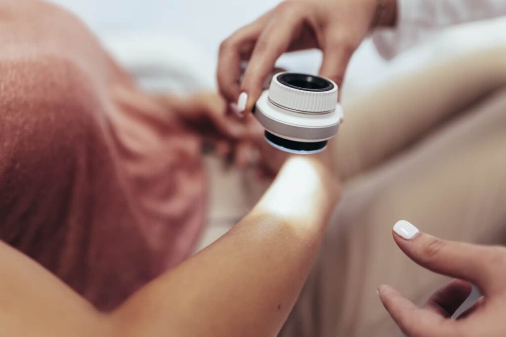 The dermatologist examines the moles or acne of the patient with a dermatoscope. Prevention of melanoma