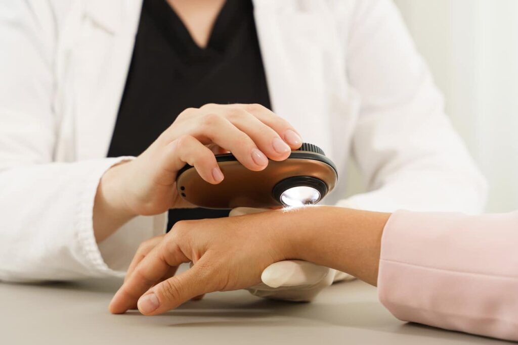 Dermatologist is using dermatoscope for skin examination.