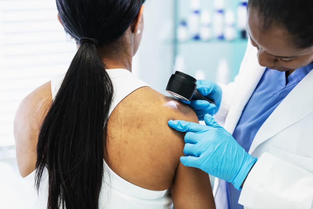 Female dermatologist screening patient for skin cancer